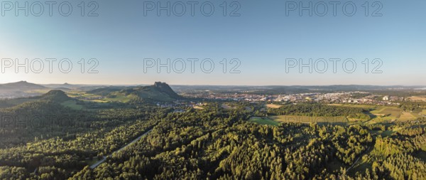 Luftbild, Panorama von einer vulkanisch geprägten Landschaft im Abendlicht, mit dem Hohenstoffeln, Hohenhewen und Hohentwiel von links gesehen, rechts am Horizont die Stadt Singen, und der angrenzenden Gemeinde Rielasingen-Worblingen, Hegau, Landkreis Konstanz, Baden-Württemberg, Deutschland