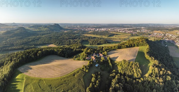 Luftbild, Panorama von einer vulkanisch geprägten Landschaft im Abendlicht, im Vordergrund der Phonolithkegel Rosenegg, am Horizont die Hegauberge mit dem Hohentwiel und der Stadt Singen mit der angrenzenden Gemeinde Rielasingen-Worblingen, Hegau, Landkreis Konstanz, Baden-Württemberg, Deutschland