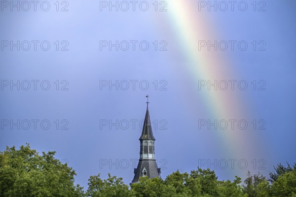 Colourful rainbow over trees and castle tower after downpour during thunderstorm in summer