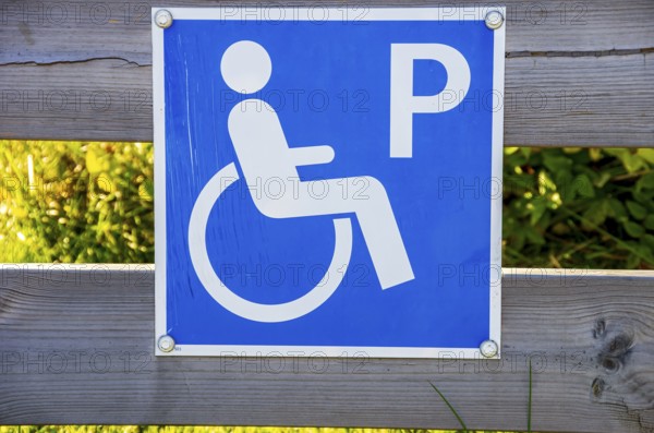 Sign with pictogram Car park for the disabled on a wooden fence, near Henan on Orust, Bohuslän, Västra Götalands län, Sweden