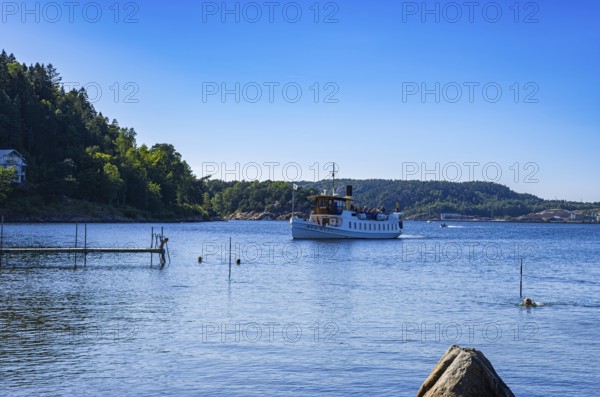The MS SUNNINGEN, an archipelago boat, approaches the landing stage in the historic seaside resort of Gustafsberg in Uddevalla, Bohuslän, Västra Götalands län, Sweden