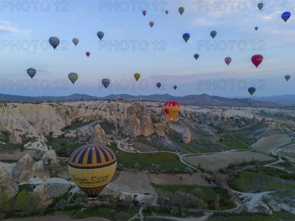 Aerial view of balloons over a vast landscape at sunrise in Cappadocia, aerial view, Göreme National Park, Göreme Tarihî Millî Parki, Nevsehir Province, Nevsehir, Cappadocia, Cappadocia, Kapadokya, Cappadocia, Central Anatolia, Turkey