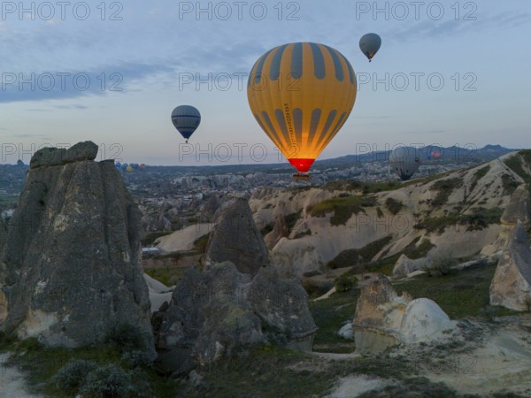 Hot air balloons hovering over a rocky landscape at dawn in Cappadocia, aerial view, Göreme National Park, Göreme Tarihî Millî Parki, Nevsehir Province, Nevsehir, Cappadocia, Cappadocia, Kapadokya, Cappadocia, Central Anatolia, Turkey