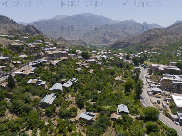 Panoramic view of a village along a road amidst green hills and mountains, aerial view, Meghri, Syunik province, mountains in the background are located in Iran, Armenia, Asia