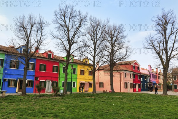 Strollers, typical street scene in winter, colourful facades of fishermen's houses in Burano, island in the lagoon of Venice, Italy