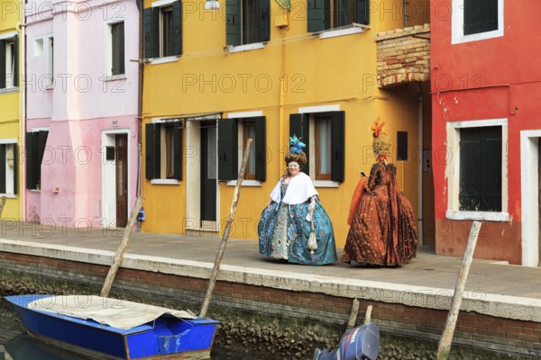 Two dressed up woman, Venetian costumes with masks, colourful facades, Burano, Venice, Veneto, Italy