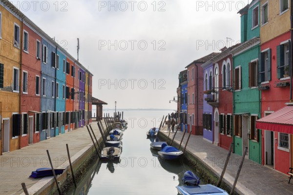 Boats on the canal, typical street scene in winter, colourful facades, various fishermen's houses in Burano, island in the lagoon of Venice, Italy