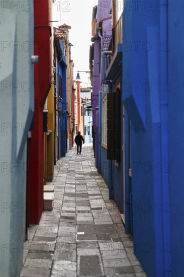 Strollers in winter, anonymous old man in a narrow alley, colourful facades, Burano, Venice, Veneto, Italy