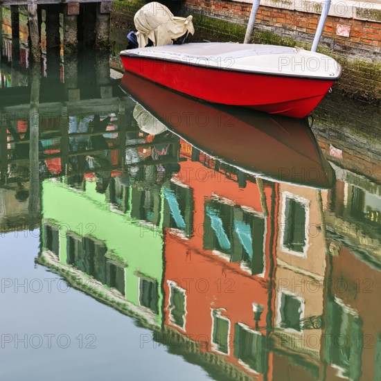 Colourful façade details reflected in the water of a canal, motorboat, Burano, Venice, Veneto, Italy