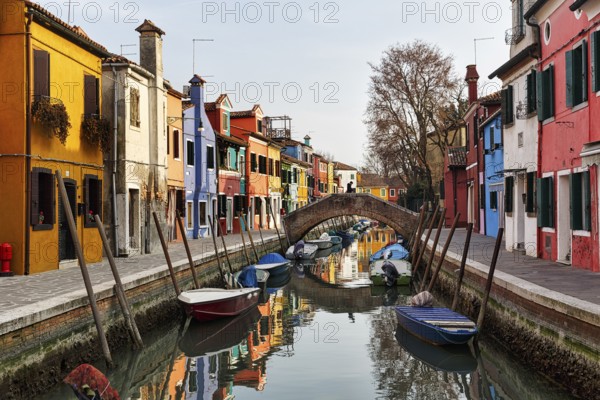Pedestrian bridge, arched bridge over canal, typical street scene in winter, colourful facades in Burano, island in the lagoon of Venice, Italy
