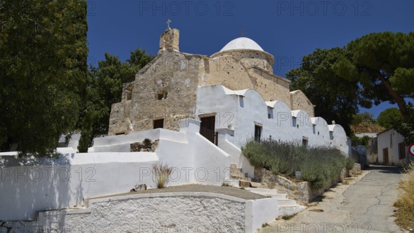Whitewashed, stone church with dome and trees under a clear blue sky, basilica, church, Agios Theologos, Leros, Dodecanese, Greek Islands, Greece