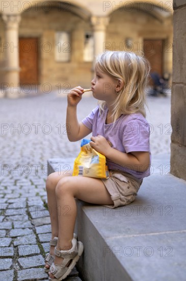 Girl, 4 years, blonde, summery dressed, sitting on step, eating biscuits, summer, Stuttgart, Baden-Württemberg, Germany