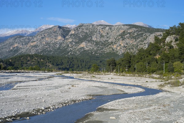 A calm river flows through a wide gravel bed, framed by forested mountains, Dargaz River near Saklikent, Saklikent, Antalya Province, Turkey