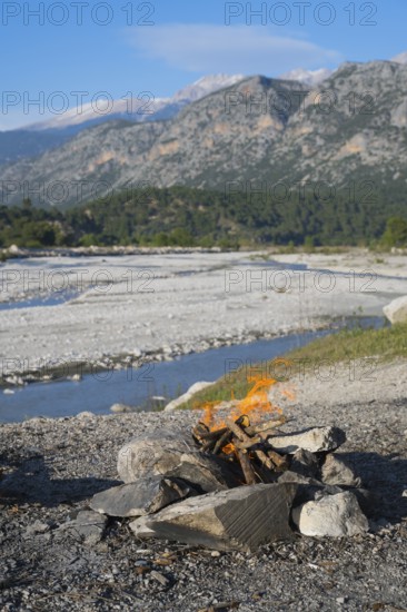 A campfire in a rocky landscape with mountains and a riverbed in the background, Dargaz River near Saklikent, Saklikent, Antalya Province, Turkey