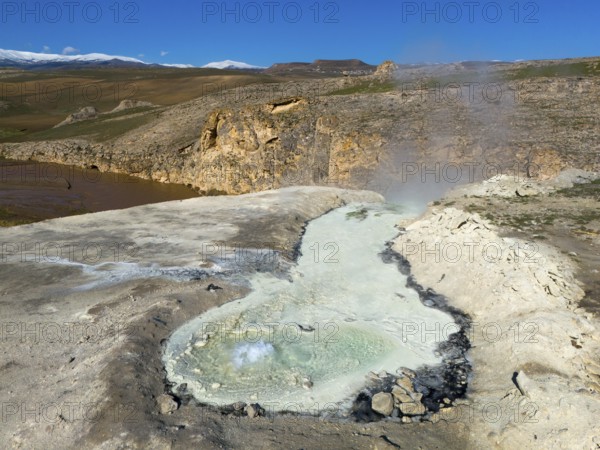 A geothermal area with a steaming geyser and rocks in a wild landscape under a blue sky, aerial view, thermal springs, Diyadin, Murat River, Agri Province, Agri, Eastern Anatolia, Turkey