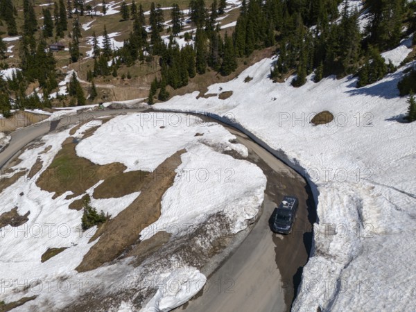Bird's eye view of a car on a snowy mountain road with curves and fir trees, aerial view, camper, motorhome, on the way to Goderdzi Pass, Adjara region, Adjara, autonomous republic, Georgia