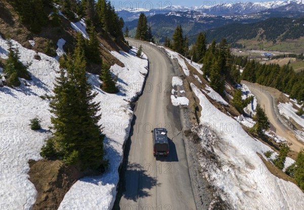 Car on winding mountain road, surrounded by snow and fir trees, with wide view, aerial view, camper, motorhome, on the way to Goderdzi Pass, Adjara region, Adjara, autonomous republic, Georgia