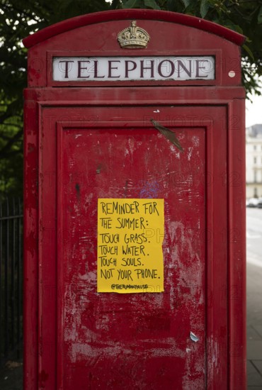 Red London telephone box with yellow poster, Kensington, London, England, Great Britain