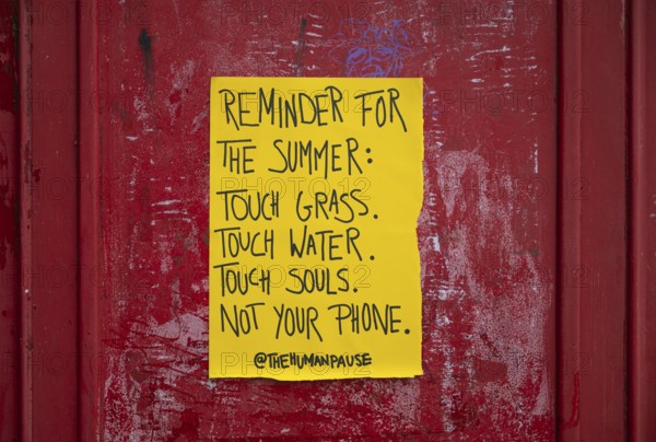 Yellow poster on phone box reminds people to appreciate nature and put their mobile phones away, Kensington, London, England, United Kingdom