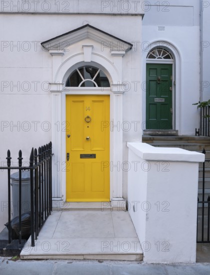 Bright yellow front door with neoclassical triangular pediment, Palladian-style entrance, white façade, Kensington, London, England, United Kingdom
