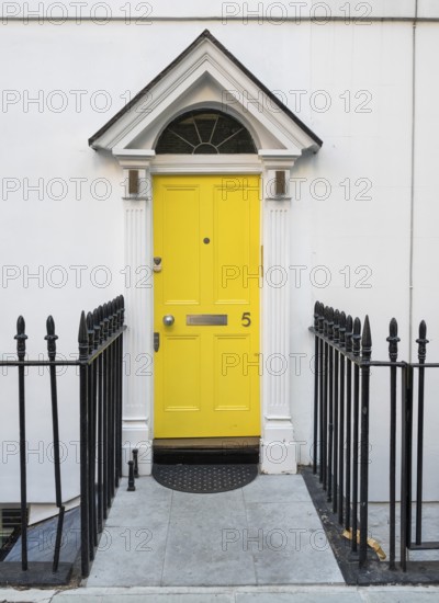 Bright yellow front door with house number five and neoclassical triangular gable, Palladian-style entrance, white façade, black fence, Kensington, London, England, United Kingdom