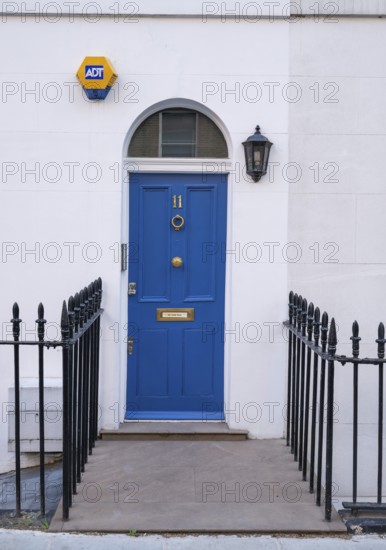 Blue door with house number 11 flanked by a lantern and a security sign, surrounded by a wrought iron fence, Kensington, London, England, United Kingdom