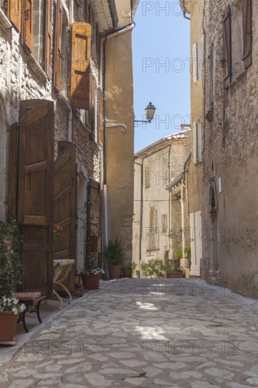 A narrow alley in a quiet village with old buildings and open shutters, Aurel, Département Vaucluse, Region Provence-Alpes-Côte d'Azur, South of France, France