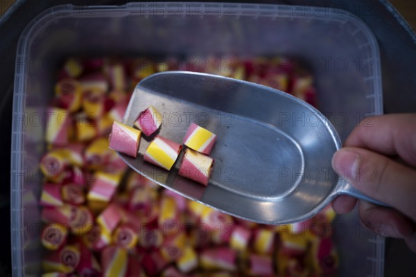 Colourful sweets are taken out of a container with a ladle, Ringkøbing, Ringkøbing Fjord, Denmark