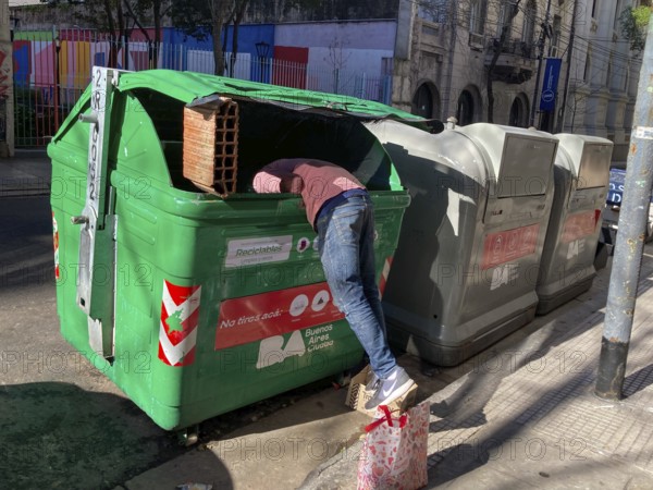 Poverty in Buenos Aires, a homeless man searches for something usable in a rubbish container, Buenos Aires, Argentina, South America
