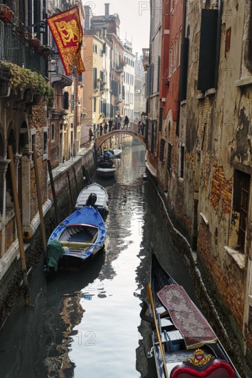 Strollers on a small bridge, boats on a canal, typical street scene in Venice, Italy