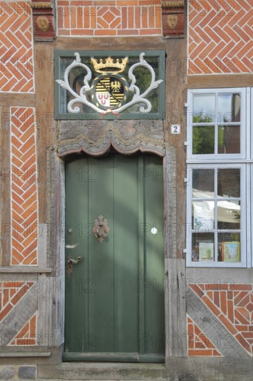 Door with coat of arms and golden crown at the entrance to the Eulenspiegel Museum, half-timbered house, Am Markt, Mölln, Schleswig-Holstein, Germany