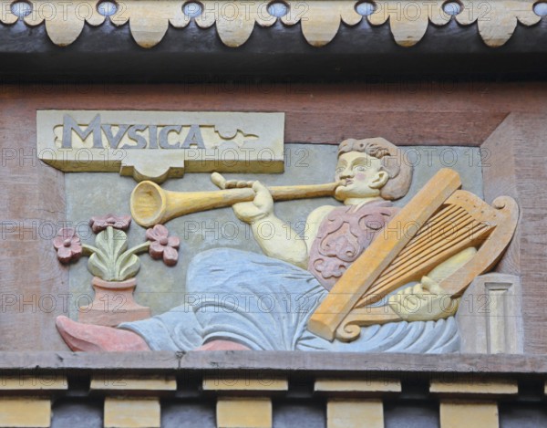 Allegorical woodcarving with figure for music with hand harp, flute and trumpet, lyre, lyre, musical instrument, making music, Renaissance, allegory, symbol, handicraft, art, historical painting, Latin inscription, detail, decoration, Wedekindhaus, Sparkasse, market square, Hildesheim, Lower Saxony, Germany