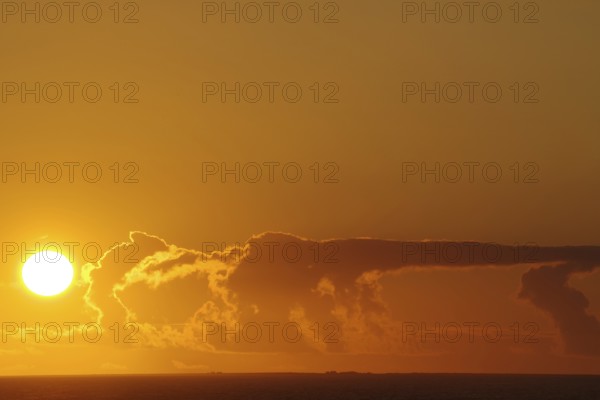 Sunset over the sea with intense orange clouds, crossing between Orkney and Shetland Islands, Scotland, Great Britain