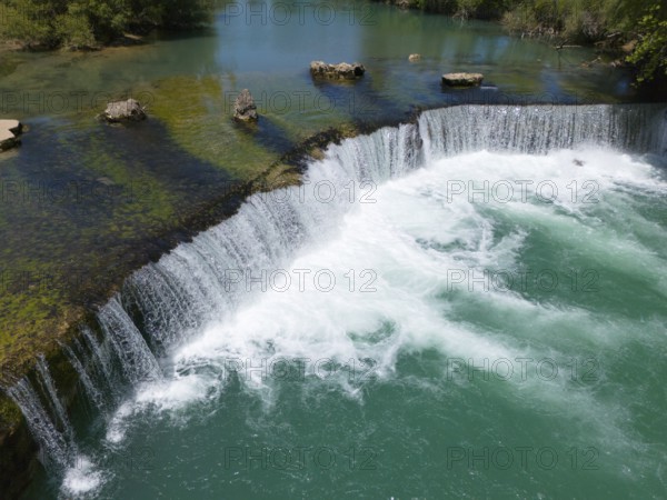 A wide waterfall with clear turquoise water, surrounded by rocks and green vegetation, aerial view, Manavgat Waterfall, Manavgat River, Side Turkey