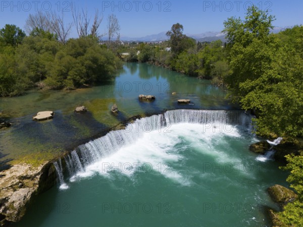 View of a waterfall and a river, surrounded by dense trees under a blue sky, aerial view, Manavgat Waterfall, Manavgat River, Side Turkey