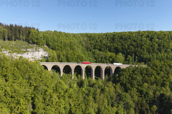 A viaduct stretches over a dense forest with vehicles on it, Drachenlochbrücke on the Drackensteiner Hang, near Drackenstein, Swabian Alb, Baden-Württemberg, Germany