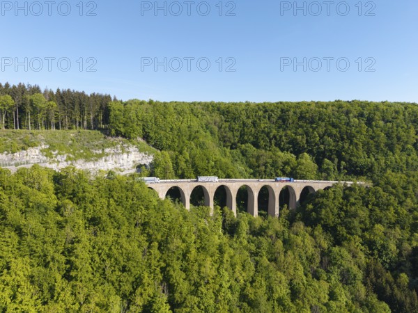 A viaduct spans a green forest while lorries pass the bridge, Drachenlochbrücke on the Drackensteiner Hang, near Drackenstein, Swabian Alb, Baden-Württemberg, Germany