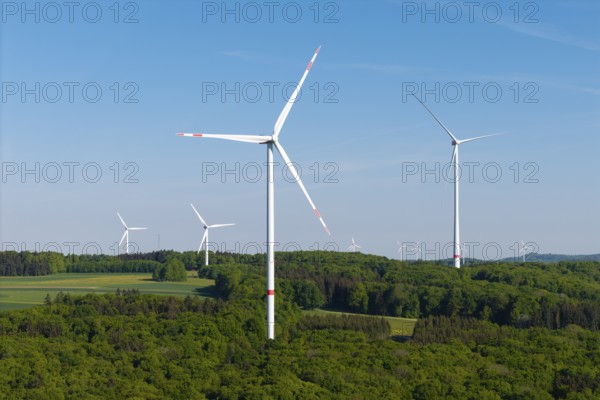 Several wind turbines in the middle of a forest under a blue sky, near Westerheim, Swabian Alb, Baden-Württemberg, Germany