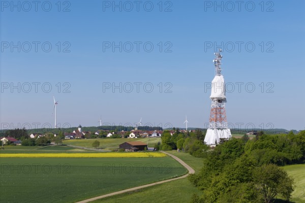 A transmission tower and wind turbines near a village under a blue sky, radio tower being renovated, near Hohenstadt, Swabian Alb, Baden-Württemberg, Germany
