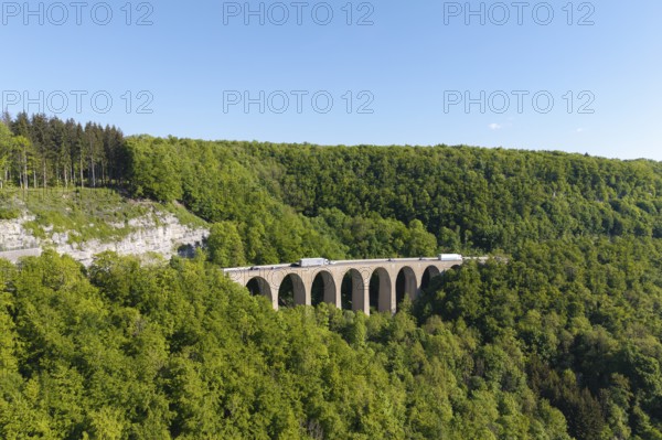A viaduct leads over a dense forest landscape under a blue sky, Drachenloch bridge on the Drackenstein slope, near Drackenstein, Swabian Alb, Baden-Württemberg, Germany