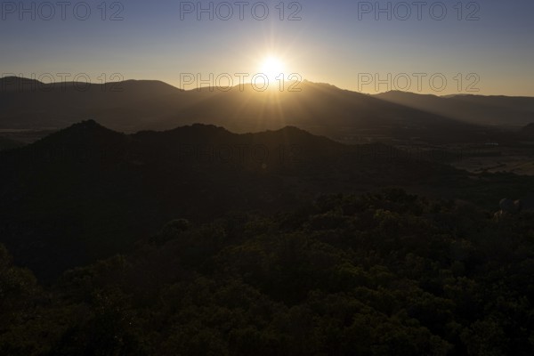 The sun sets behind the mountains on the Mediterranean island of Sardinia, Monte Nai, Costa Rei, Sardinia, Italy