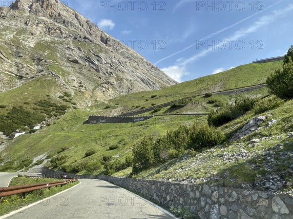 View of the Alpine road in front Mountain road at tree line, in the centre of the picture serpentine bends built into the mountainside Bends from pass road South ramp south-western ascent Descent from the Stelvio Pass towards Bormio, Province of Sondrio, Lombardy, Italy