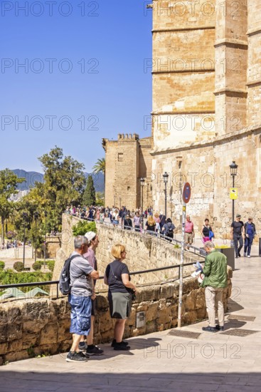 Tourists by a wall outside the Palma Cathedral a sunny summer day, Palma de Mallorca, Mallorca, Spain