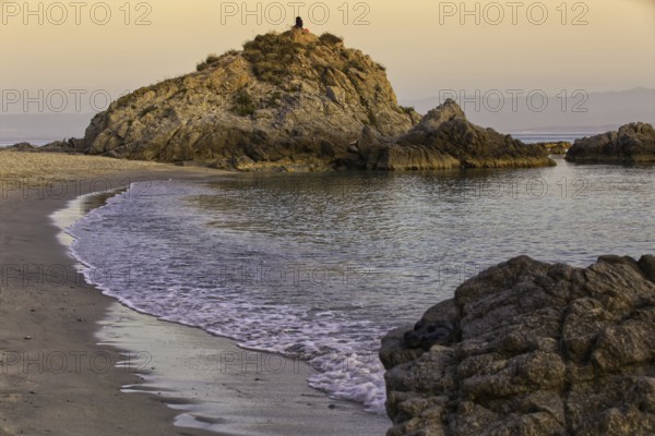 Rocky beach at sunset with gentle waves and a calm atmosphere, Ricadi, Capo Vaticano