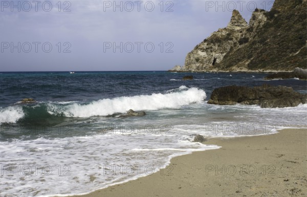 Waves rolling over the sandy beach, rocky coast in the distance, Ricadi, Capo Vaticano