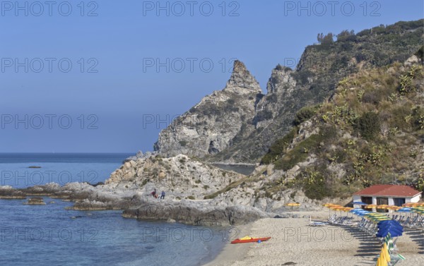 Rocky beach with parasols and buildings on the coast of the blue sea, Ricadi, Capo Vaticano