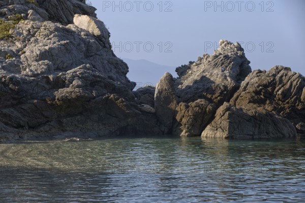 Shaded rocky coast with calm waters under a blue sky, Ricadi, Capo Vaticano