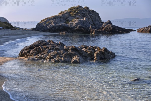 Clear waves lapping rocky coast with calm sea and bright beach, Ricadi, Capo Vaticano