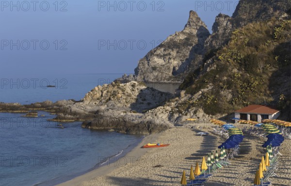 Quiet beach with parasols in front of a rocky coast and blue sea, Ricadi, Capo Vaticano