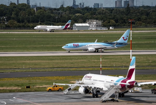 Düsseldorf Airport, Eurowings Airbus aircraft on the apron, TUI Boeing 737-800 on take-off, Eurowings Airbus after landing, in the background the HKM steelworks in Duisburg, North Rhine-Westphalia, Germany